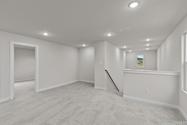 below grade area with recessed lighting, light carpet, visible vents, and baseboards