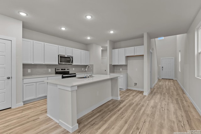 kitchen featuring light wood-style flooring, stainless steel appliances, a sink, white cabinetry, and light countertops