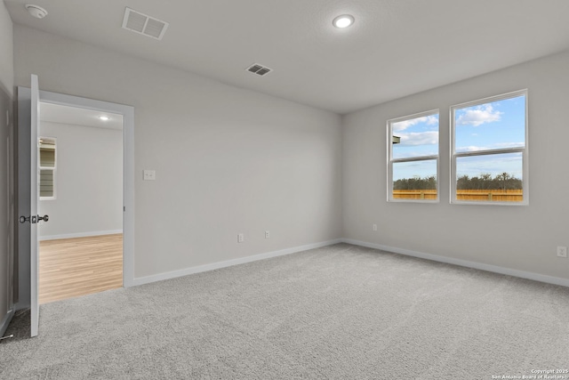 unfurnished room with light colored carpet, visible vents, and baseboards