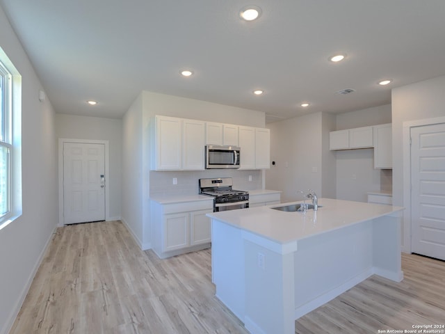 kitchen featuring stainless steel appliances, sink, a center island with sink, and white cabinets