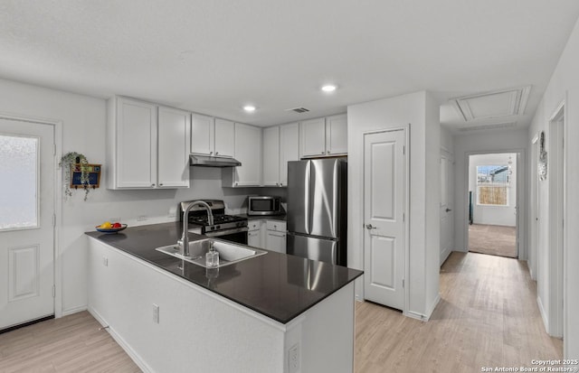 kitchen featuring sink, white cabinetry, light wood-type flooring, appliances with stainless steel finishes, and kitchen peninsula