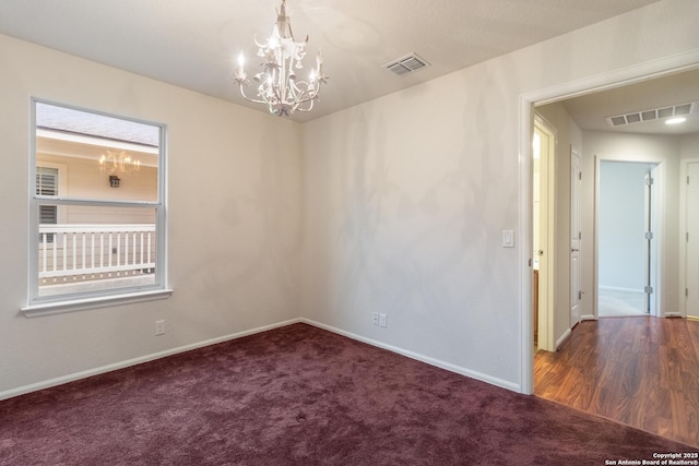 carpeted empty room featuring a notable chandelier