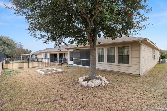 rear view of property featuring a yard, a sunroom, and central air condition unit