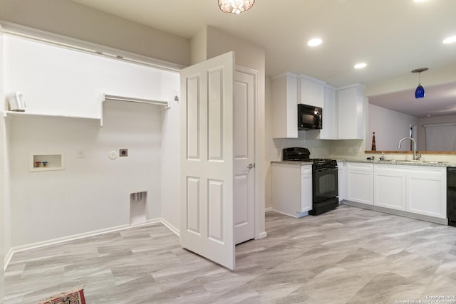 kitchen with white cabinetry, sink, light stone counters, and black appliances