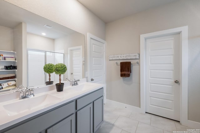 bathroom with a shower with door, vanity, and tile patterned flooring