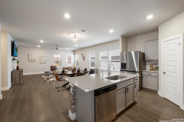 kitchen with appliances with stainless steel finishes, sink, a kitchen island with sink, and gray cabinetry