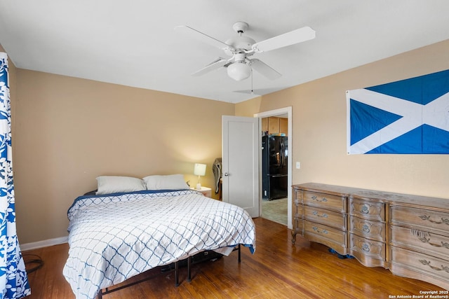 bedroom featuring black refrigerator, dark hardwood / wood-style floors, and ceiling fan