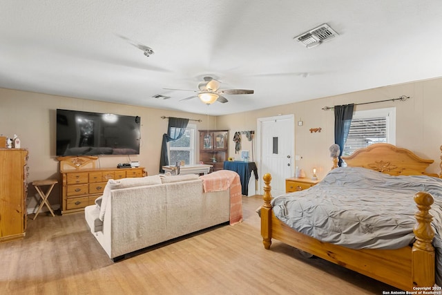 bedroom with a textured ceiling, light hardwood / wood-style flooring, and ceiling fan