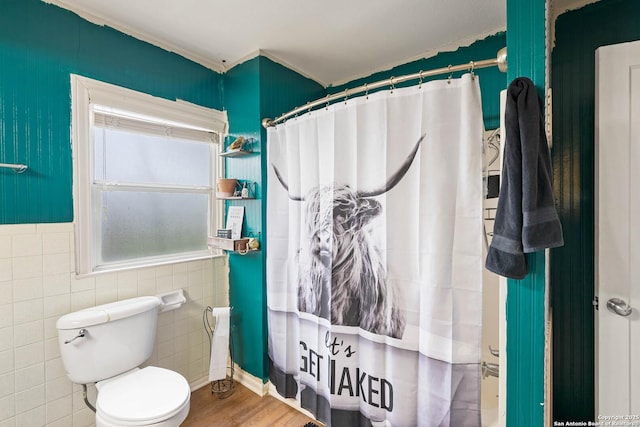 bathroom with toilet, curtained shower, hardwood / wood-style floors, and tile walls