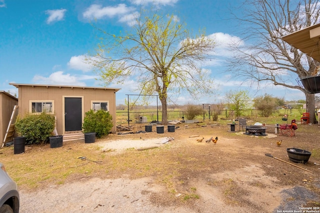 view of yard featuring an outdoor structure and an outdoor fire pit