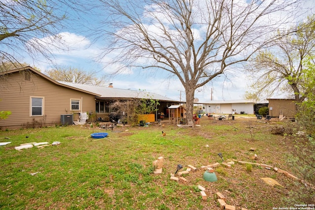 rear view of property featuring central AC unit and a lawn