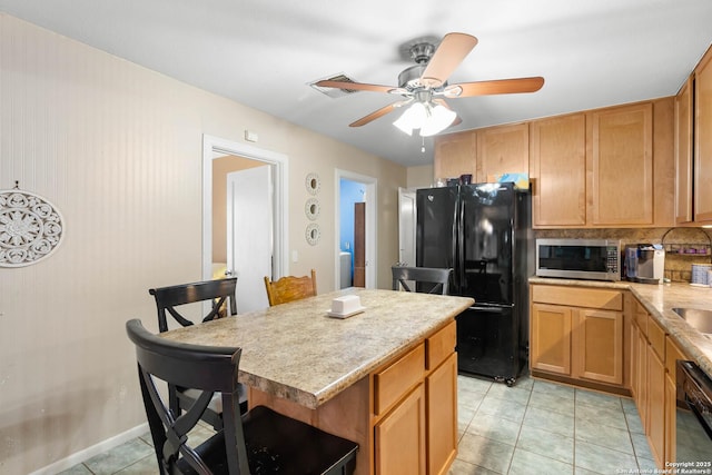 kitchen featuring tasteful backsplash, a center island, light tile patterned floors, ceiling fan, and black appliances