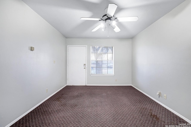 spare room with dark colored carpet and ceiling fan