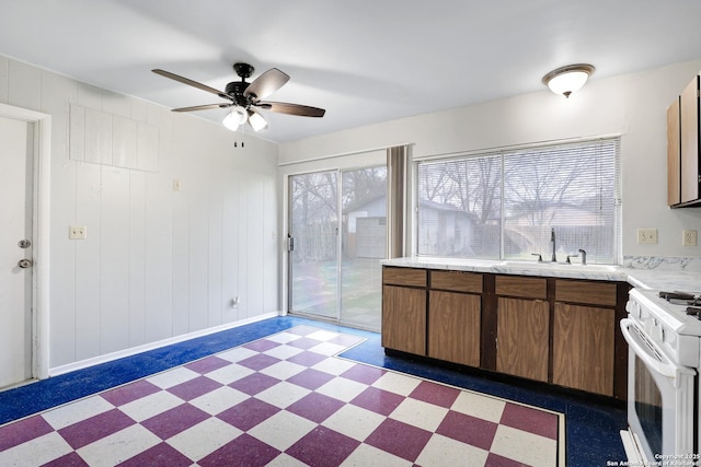 kitchen featuring white gas range, a healthy amount of sunlight, sink, and ceiling fan