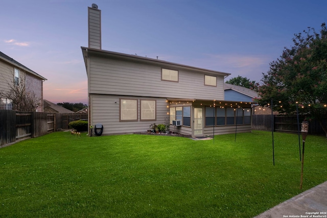 back house at dusk featuring cooling unit, a yard, and a sunroom