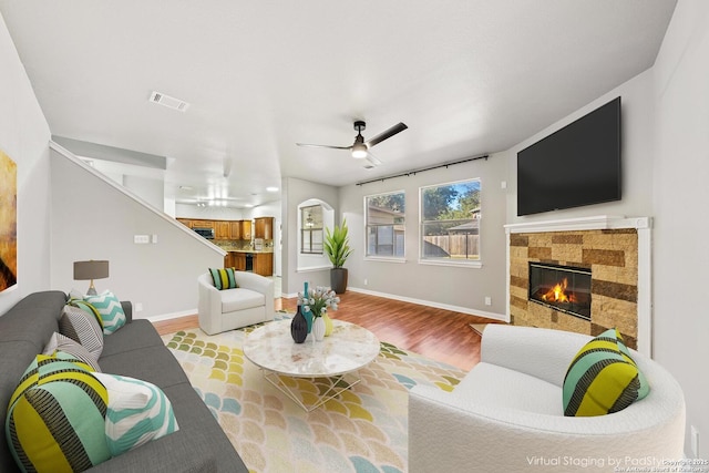 living room featuring ceiling fan, light hardwood / wood-style floors, and a tile fireplace