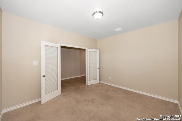 unfurnished bedroom with light colored carpet and a closet