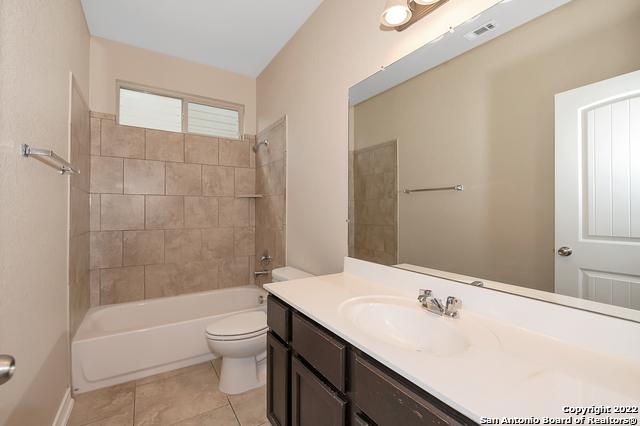 full bathroom with tiled shower / bath, vanity, tile patterned floors, and toilet