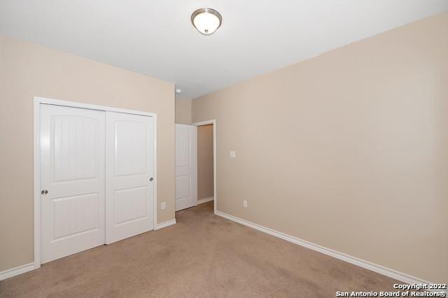 unfurnished bedroom with light carpet and a closet