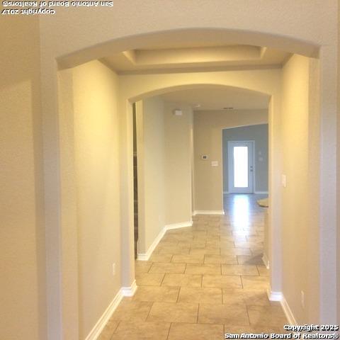 hall with baseboards and a raised ceiling