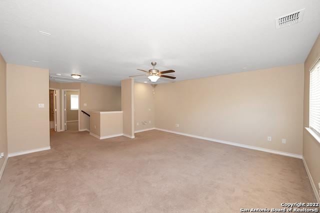 carpeted spare room featuring ceiling fan and plenty of natural light