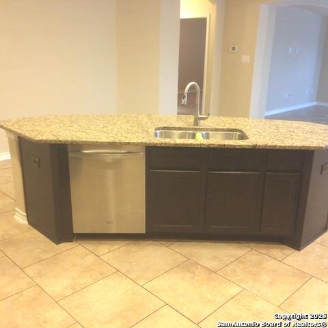 kitchen featuring light stone countertops, sink, stainless steel dishwasher, and light tile patterned floors