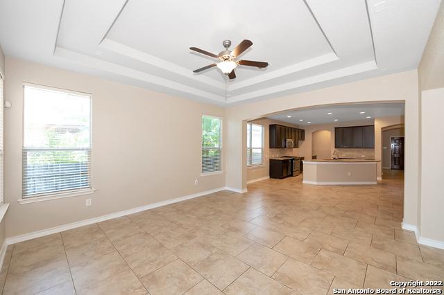 unfurnished living room with ceiling fan, a tray ceiling, and a wealth of natural light