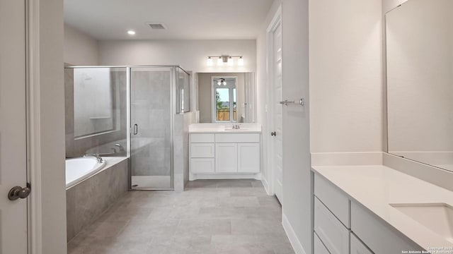 full bathroom with a garden tub, visible vents, a stall shower, two vanities, and a sink