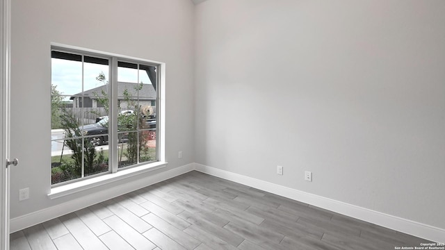 spare room featuring baseboards and wood finished floors