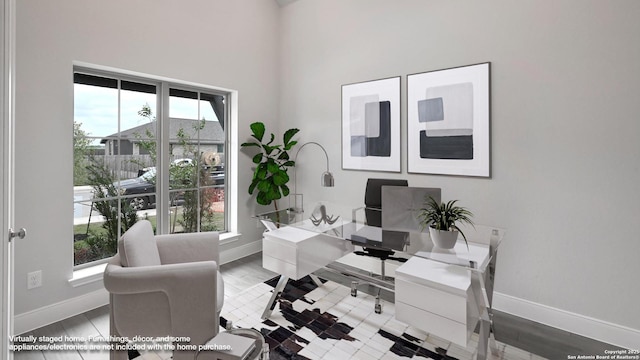 home office with baseboards, a high ceiling, and a healthy amount of sunlight