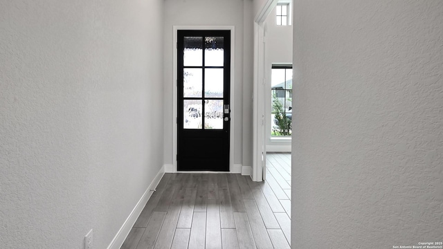 entryway with baseboards, a textured wall, and wood finished floors