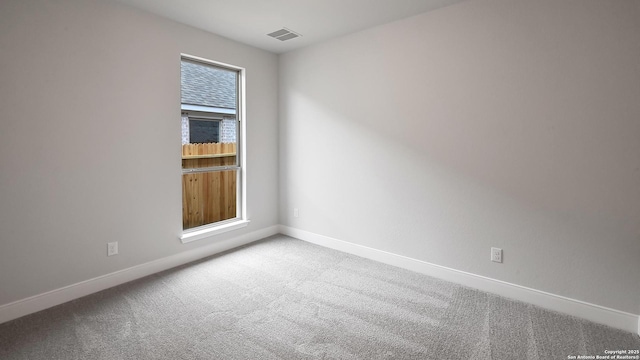 spare room with carpet flooring, baseboards, and visible vents