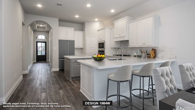 kitchen featuring sink, white cabinetry, appliances with stainless steel finishes, dark hardwood / wood-style flooring, and kitchen peninsula