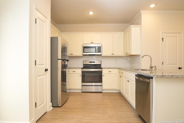 kitchen with sink, white cabinetry, backsplash, stainless steel appliances, and light stone countertops