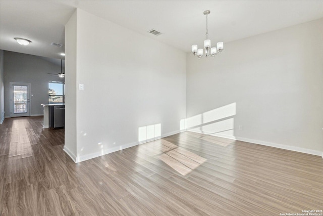 spare room with hardwood / wood-style flooring and a notable chandelier