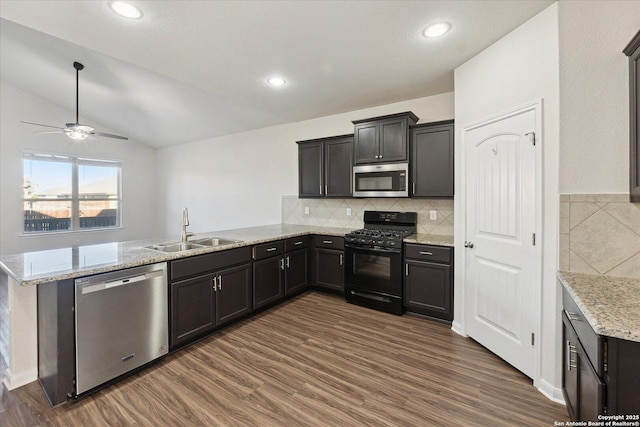 kitchen with appliances with stainless steel finishes, tasteful backsplash, lofted ceiling, sink, and kitchen peninsula