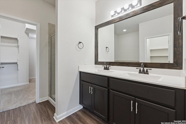 bathroom with wood-type flooring, a shower with door, and vanity