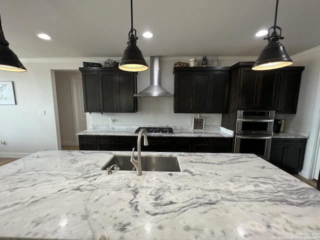 kitchen featuring appliances with stainless steel finishes, sink, hanging light fixtures, crown molding, and wall chimney exhaust hood