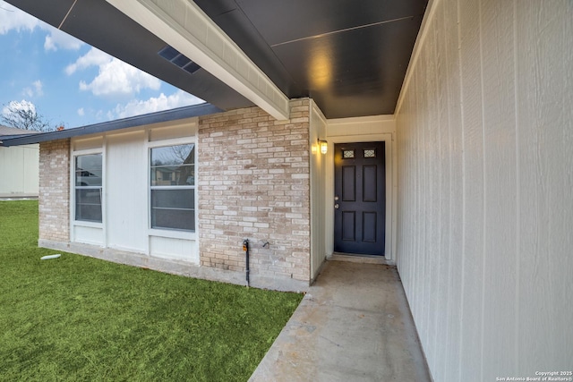 view of exterior entry with a yard