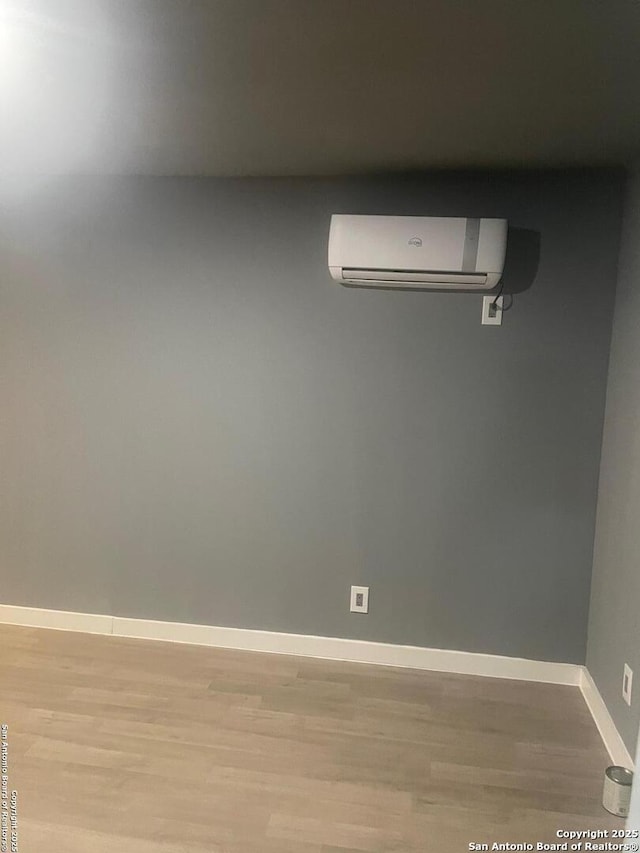 unfurnished room featuring a wall unit AC and light wood-type flooring