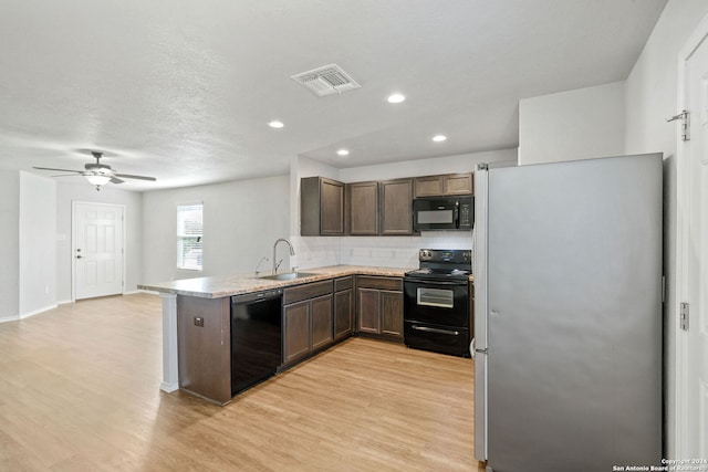 kitchen featuring sink, light hardwood / wood-style flooring, backsplash, black appliances, and kitchen peninsula