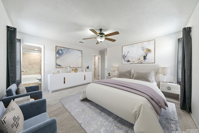 carpeted bedroom with ensuite bath, a textured ceiling, and ceiling fan