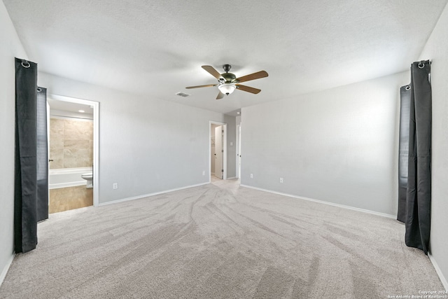 unfurnished bedroom featuring ensuite bath, light colored carpet, ceiling fan, and a textured ceiling