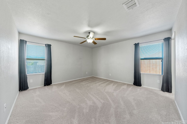 carpeted empty room with a textured ceiling, a wealth of natural light, and ceiling fan