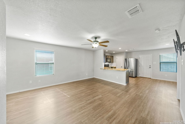 unfurnished living room featuring ceiling fan, a textured ceiling, and light hardwood / wood-style floors