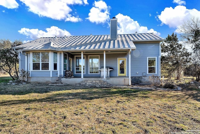 rear view of house featuring a lawn and a porch