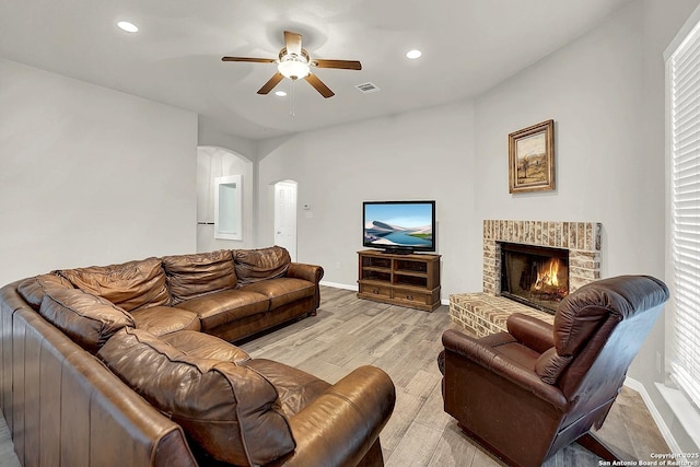 living room featuring ceiling fan, a fireplace, and light hardwood / wood-style flooring