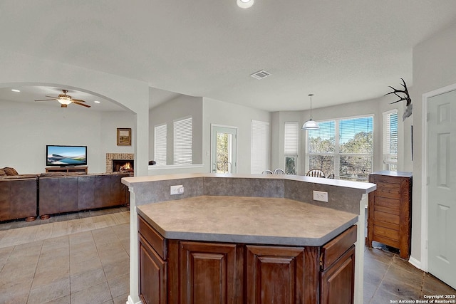 kitchen featuring ceiling fan, decorative light fixtures, a kitchen island, and a textured ceiling