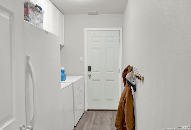 laundry area with cabinets, washing machine and dryer, and light wood-type flooring