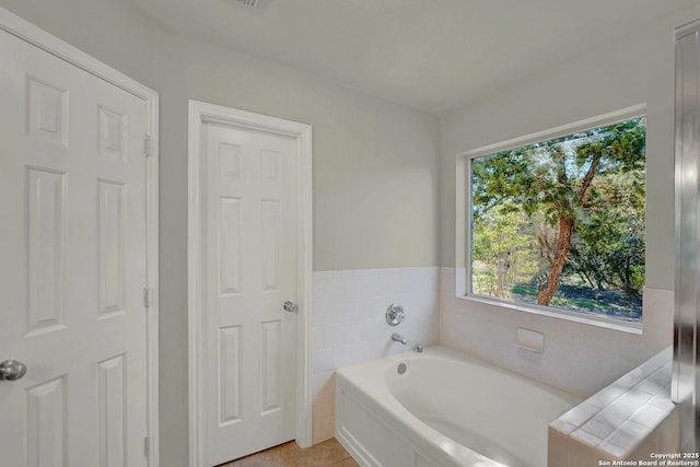 bathroom with a healthy amount of sunlight, a washtub, and tile patterned floors